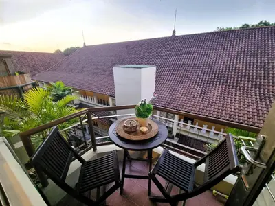 a balcony with a table and chairs and a roof at Mana Suites Bali in Kuta