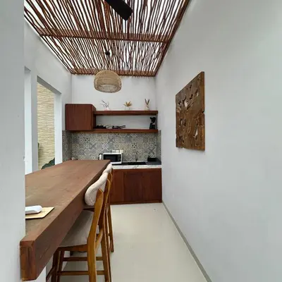 a kitchen with a wooden table and chairs at Maithala Villa & Living in Kuta