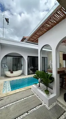 a villa with a swimming pool and a house at Maithala Villa & Living in Kuta
