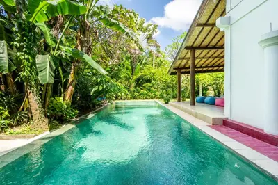 a swimming pool in front of a house with trees at Bali Dream Villa Legian by iBali Management in Seminyak