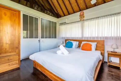 a bedroom with a large white bed with orange and blue pillows at Bali Dream Villa Legian by iBali Management in Seminyak