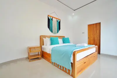 a bedroom with a wooden bed with blue pillows at Robelle Villa by iBali Management in Seminyak