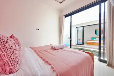 a bedroom with a pink bed with a large window at Robelle Villa by iBali Management in Seminyak