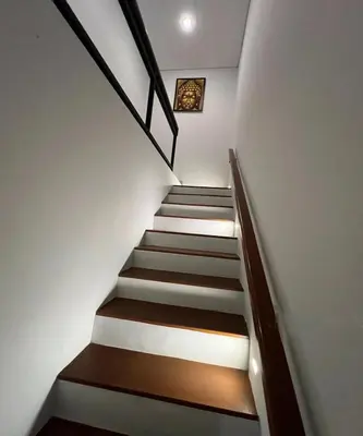 a stairway with white walls and wooden stairs at Villa Dharman Jimbaran in Jimbaran