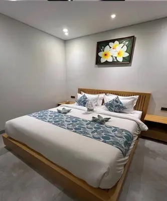 a bedroom with a large bed with a flower painting on the wall at Villa Dharman Jimbaran in Jimbaran