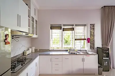 a white kitchen with a sink and a window at Casa Raya 4BR Villa in Kuta in Kuta