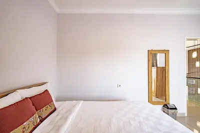 a white bedroom with a bed and a mirror at Casa Raya 4BR Villa in Kuta in Kuta