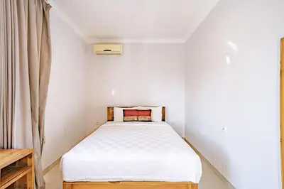a small white bedroom with a bed and a window at Casa Raya 4BR Villa in Kuta in Kuta