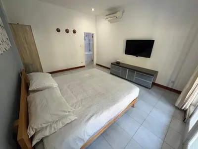 a bedroom with a large bed and a flat screen tv at Villa central seminyak in Seminyak