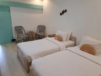 two beds in a room with chairs and a table at Lavender Villa 7 Moon House in Kuta