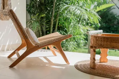 a rattan chair next to a wooden table at Villa Anna Lou 1BR Boho Escape in Seminyak in Seminyak