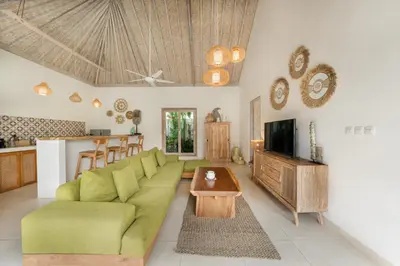 a living room with a green couch and a tv at Villa Anna Lou 1BR Boho Escape in Seminyak in Seminyak