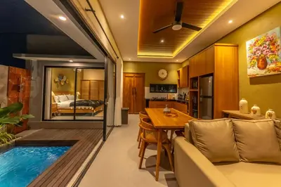 a living room and dining room with a swimming pool at Villa Sattvika in Kerobokan