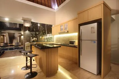 a kitchen with a refrigerator and a bar with a stool at Djayana Villa Seminyak in Seminyak