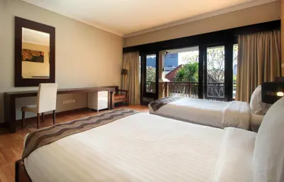 a hotel room with two beds and a desk and window at Djayana Villa Seminyak in Seminyak