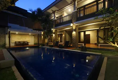 a swimming pool in front of a house at night at Djayana Villa Seminyak in Seminyak