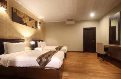a hotel room with two beds and a desk at Djayana Villa Seminyak in Seminyak