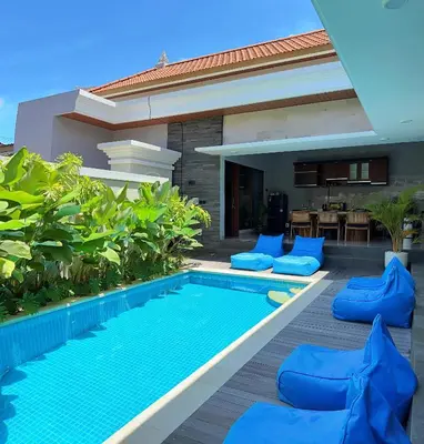 a swimming pool with blue chairs next to a house at Villa Sakura Nisa in Seminyak