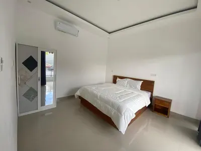 a white bedroom with a bed and a window at Hidden Homestay Jimbaran in Jimbaran