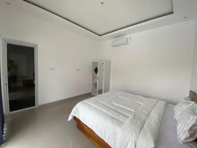 a white bedroom with a bed and a window at Hidden Homestay Jimbaran in Jimbaran
