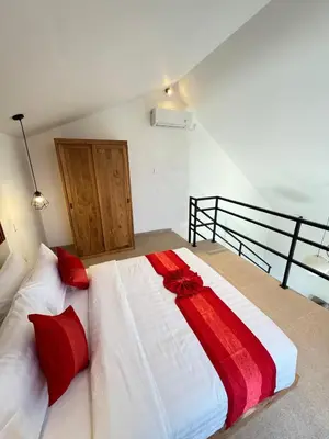 a bedroom with a white bed with red pillows at Kubumanik Loft in Seminyak