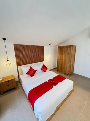 a bedroom with a large white bed with red pillows at Kubumanik Loft in Seminyak