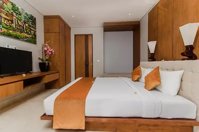 a bedroom with a large white bed and a flat screen tv at Villa By The Sea with private swimming pool in Benoa - Nusa Dua in Ujung