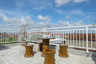 a balcony with a table and some logs at Urbanview Hotel Arta Guna Casa in Kerobokan