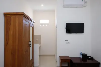 a room with a wooden door and a tv on the wall at Urbanview Hotel Arta Guna Casa in Kerobokan