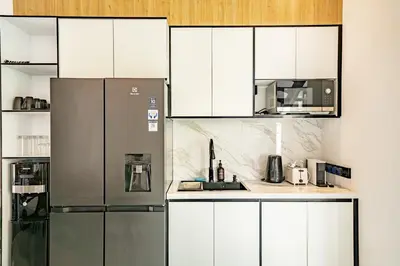 a kitchen with white cabinets and a stainless steel refrigerator at Aya Townhouses - Prime Location Umalas in Kerobokan