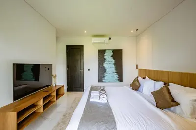a bedroom with a large bed and a flat screen tv at Aya Townhouses - Prime Location Umalas in Kerobokan