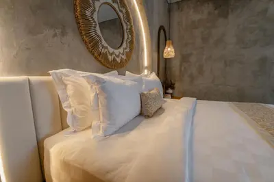 a bedroom with a white bed with a mirror on the wall at Dharman Royal Villas in Kerobokan