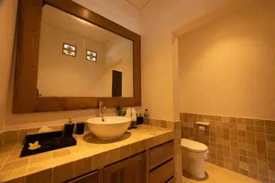a bathroom with a sink and a toilet and a mirror at Astamaya Signature Villas in Seminyak