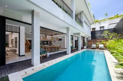 an indoor pool with a dining area and a house at Astamaya Signature Villas in Seminyak