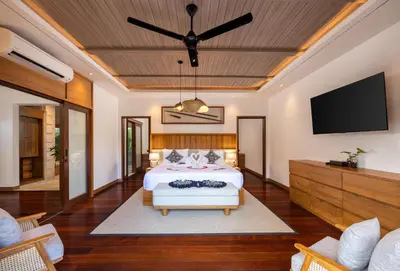 a bedroom with a bed and a flat screen tv at Astamaya Signature Villas in Seminyak