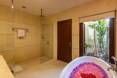 a bathroom with a shower and a tub with a sink at Aragreen Berawa Villa in Canggu
