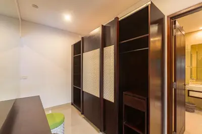 a walk in closet with dark wood cabinets and a green stool at Aragreen Berawa Villa in Canggu