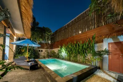 a swimming pool with a chair and an umbrella at Villa De Ocean in Seminyak