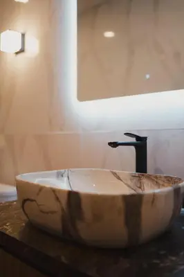 a stone sink in a bathroom with a mirror at Dikubu Belong VILLA in Denpasar