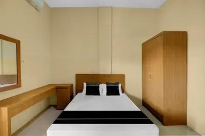 a bedroom with a bed with a wooden headboard at Hotel O near Trans Studio Theme Park formerly Cyloam Residence in Legian