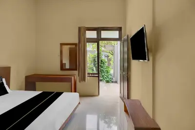 a bedroom with a bed and a tv and a window at Hotel O near Trans Studio Theme Park formerly Cyloam Residence in Legian
