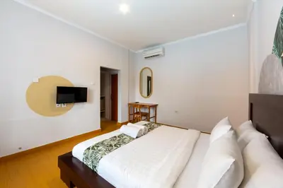 a bedroom with a bed and a tv on the wall at Cove De Pavilla in Sanur