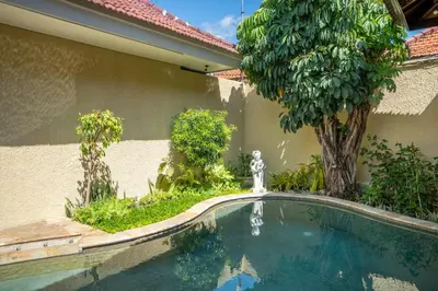 a swimming pool in front of a house with a tree at Villa PBC 2 Bed Room Private Pool in Seminyak in Seminyak