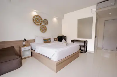 a white bedroom with a bed and a couch at Homely Bali at Rajapala in Seminyak