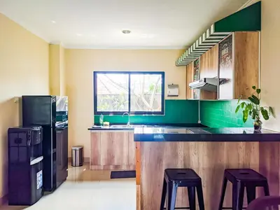 a kitchen with green walls and a counter with stools at The Lavana Villa Singgahan Jimbaran - 3 Bedroom Villa in Nusa Dua