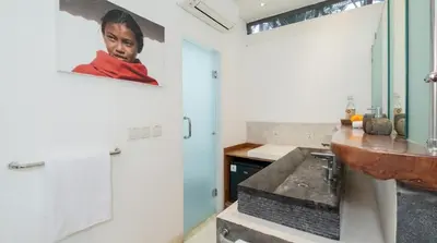 a bathroom with a sink and a counter with a picture of a boy at Villa Bidadari With Pool in Seminyak