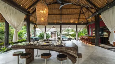 an outdoor dining area with a large stone table and stools at Villa Bidadari With Pool in Seminyak