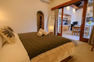 a bedroom with a large bed and a dining room at New Vindra I Villa 2BR in the heart of Berawa in Canggu