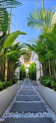 a walkway through a building with palm trees at Villa Alkasa - Legian 400m to beach in Badung