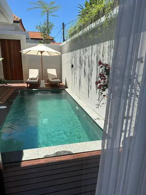a swimming pool with two chairs and an umbrella at Villa Alkasa - Legian 400m to beach in Badung